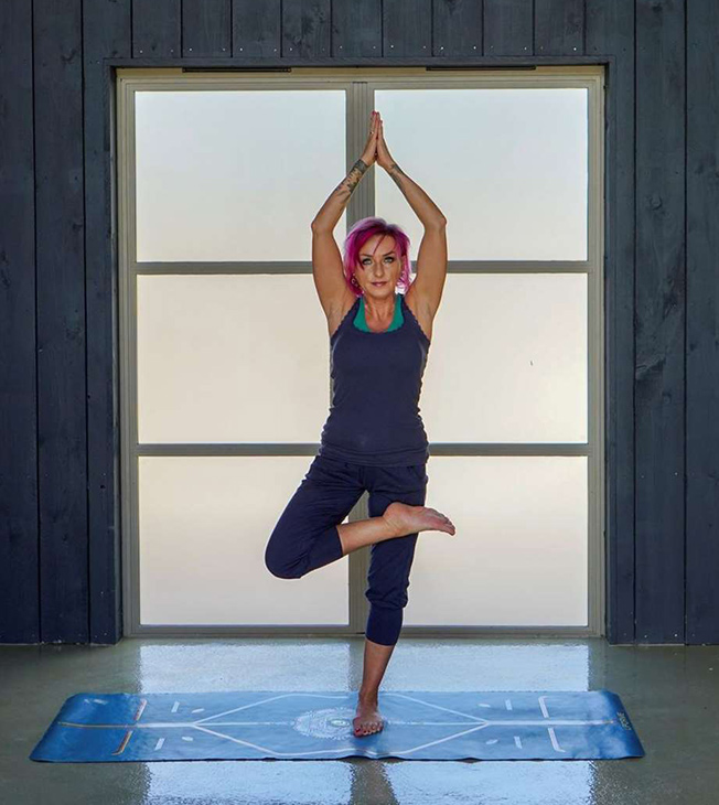 jacqui performing yoga pose in front of frosted windows